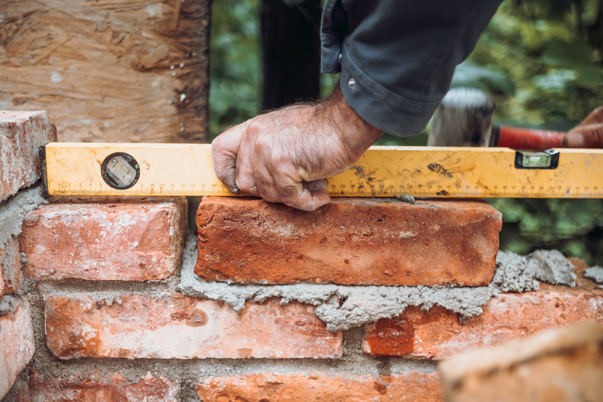 closeup of construction worker installing bricks using level, building house